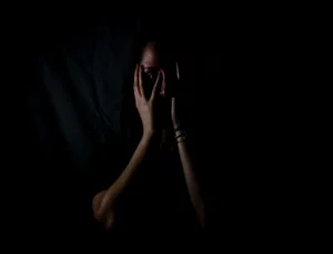 Person holding their face in the dark